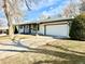 View of the white brick exterior of the house with an attached two car garage and concrete driveway at 1630 S Valentine Way, Lakewood, CO 80228