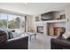 Bright living room features a cozy fireplace, tv, and large windows overlooking the yard at 11866 High Desert Rd, Parker, CO 80134