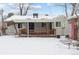 Exterior of home with backyard and covered wood deck with railings, surrounded by a snowy landscape at 7135 W 24Th Ave, Lakewood, CO 80214