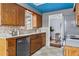 Well-lit galley kitchen featuring wood cabinetry, stainless steel appliances, and tile flooring with a blue ceiling at 7135 W 24Th Ave, Lakewood, CO 80214