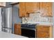 Kitchen featuring a stainless steel refrigerator and range oven with wood cabinets and tiled backsplash at 7135 W 24Th Ave, Lakewood, CO 80214