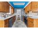 Well-lit galley kitchen featuring wood cabinetry, stainless steel appliances, and tile flooring with a blue ceiling at 7135 W 24Th Ave, Lakewood, CO 80214