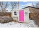 A small shed with a vibrant pink door, a window with shutters, and a small planter at 7135 W 24Th Ave, Lakewood, CO 80214