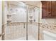 Bathroom shower with glass doors, tiled walls with mosaic accents, and built-in shelves at 5429 S Waco St, Centennial, CO 80015