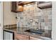Well-lit wet bar features stone tile backsplash, granite countertop, undermount sink, and stainless steel beverage refrigerator at 5429 S Waco St, Centennial, CO 80015