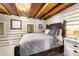 Serene bedroom featuring a carved wooden headboard, wood beam ceilings, and natural lighting at 9506 S Deer Creek Canyon Rd, Littleton, CO 80127