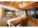 Open dining room with wood table, chairs and ceiling, and a view of the kitchen at 9506 S Deer Creek Canyon Rd, Littleton, CO 80127