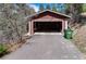 Exterior of a two-car garage with an asphalt driveway and a green trash receptacle at 9506 S Deer Creek Canyon Rd, Littleton, CO 80127