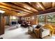 Warm living room with wood ceiling, stone fireplace, plush seating, and large windows at 9506 S Deer Creek Canyon Rd, Littleton, CO 80127