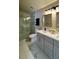 A stylish bathroom featuring a glass enclosed shower, double sinks, and grey cabinets at 13612 Plaster Cir, Broomfield, CO 80023