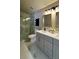 A stylish bathroom featuring a glass enclosed shower, double sinks, and grey cabinets at 13612 Plaster Cir, Broomfield, CO 80023
