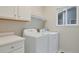 Functional laundry room with white appliances, overhead storage, and a convenient folding counter at 13612 Plaster Cir, Broomfield, CO 80023