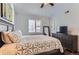 Inviting bedroom features a ceiling fan, neutral walls, shutters, dark wood frame bed, and a chest of drawers at 5420 Allison St # 202, Arvada, CO 80002