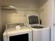 Functional laundry room featuring a modern washer and dryer set with overhead shelving for storage at 5420 Allison St # 202, Arvada, CO 80002