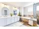 Modern bathroom featuring dual sinks, arched mirrors, soaking tub with decorative stone, and glass enclosed shower at 9804 N Crystal Lake Dr, Littleton, CO 80125