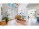 Sun-filled living room with tall ceilings, dark wood floors, large windows and a beautiful chandelier above a piano at 9804 N Crystal Lake Dr, Littleton, CO 80125