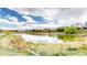 Scenic view of a calm pond reflecting the sky, with houses and grassy shore in the background at 9804 N Crystal Lake Dr, Littleton, CO 80125