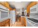A well-lit kitchen featuring wood cabinets, white appliances, and an open layout at 1400 S Knox Ct, Denver, CO 80219