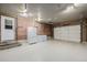 Spacious garage with epoxy flooring, brick accent wall, freezer, and an insulated garage door at 9170 Aspen Dr, Thornton, CO 80229