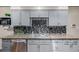 Modern kitchen with stainless steel dishwasher, granite countertops, gray cabinets and mosaic backsplash at 9170 Aspen Dr, Thornton, CO 80229