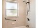 Bathroom with accessible grab bar, window, tile surround, and shower head at 5556 Vaughn St, Denver, CO 80239