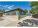 Charming home features a green exterior, brick accents, and a paved driveway leading to a detached garage at 5556 Vaughn St, Denver, CO 80239