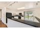 White kitchen cabinets accent black countertops and appliances, with ample natural light at 5556 Vaughn St, Denver, CO 80239