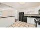 White kitchen cabinets, tiled floor, black appliances complement eating space at 5556 Vaughn St, Denver, CO 80239