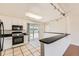 Well-lit kitchen featuring black appliances, white cabinets, and tiled flooring at 5556 Vaughn St, Denver, CO 80239