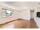 Bright living room featuring hardwood floors, a large window, and a view of the connected kitchen at 5556 Vaughn St, Denver, CO 80239