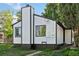 Back exterior of home with black trim and chimney, set against a backdrop of mature trees at 2430 Eaton St, Edgewater, CO 80214