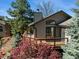 Beautiful home featuring a charming deck, lush landscaping, mature trees and architectural details at 837 Meadow Run, Golden, CO 80403