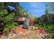 Exterior view of a charming home with a wooden deck, surrounded by mature trees and a well-maintained garden at 837 Meadow Run, Golden, CO 80403