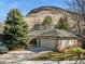 Garage exterior with stone details, well-manicured grass, and mountain backdrop at 837 Meadow Run, Golden, CO 80403