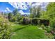 Lush backyard with manicured lawn, blooming flowers and a charming garden gate at 1795 N Monaco St Pkwy, Denver, CO 80224