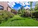 Expansive green backyard with lush lawn, mature trees, and manicured garden beds at 1795 N Monaco St Pkwy, Denver, CO 80224