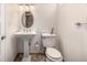 Elegant powder room with pedestal sink, oval mirror and classic toilet at 1795 N Monaco St Pkwy, Denver, CO 80224