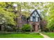 Charming stone Tudor home with a manicured front yard, a stone walkway leading to the front door, and lush landscaping at 1795 N Monaco St Pkwy, Denver, CO 80224