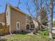 View of the rear exterior featuring a patio, lawn, mature tree and a stone chimney at 13598 E Asbury Dr, Aurora, CO 80014