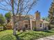 Rear exterior showcasing the patio, lush lawn, stone chimney, and well-maintained siding at 13598 E Asbury Dr, Aurora, CO 80014