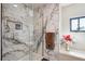 Modern shower featuring marble tiling, a glass door, and a built-in shelf at 1913 Five Iron Dr, Castle Rock, CO 80104