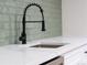 Close-up of a modern kitchen sink featuring a matte black faucet, white countertop, and light green backsplash at 1248 Ilium Dr, Lafayette, CO 80026