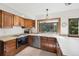Well-lit kitchen with wood cabinets, stainless steel dishwasher, and a window above the sink looking to the backyard at 4626 E Links Dr, Centennial, CO 80122