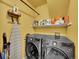 Functional laundry room with modern washer and dryer, storage shelf, and ironing board at 1052 Northampton Ct, Highlands Ranch, CO 80126