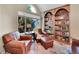 Cozy living room featuring comfortable leather chairs, a bookshelf, and an arched window at 1052 Northampton Ct, Highlands Ranch, CO 80126