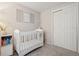 Bright bedroom with a white crib, closet, decorative wall art, and neutral carpet at 7049 E Briarwood Cir, Centennial, CO 80112