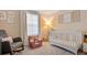 Well-lit bedroom with a gray and pink chair, crib, neutral walls and carpet at 7049 E Briarwood Cir, Centennial, CO 80112