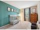 Charming bedroom with a gray crib, wood dresser, window, and a teal accent wall at 7049 E Briarwood Cir, Centennial, CO 80112