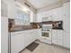 Well-lit kitchen with white cabinets, tiled counters, and modern appliances at 7049 E Briarwood Cir, Centennial, CO 80112