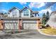 Two-story townhome featuring attached garages, gray siding and brick accents under a bright blue, partly cloudy sky at 7707 S Monaco Cir, Centennial, CO 80112